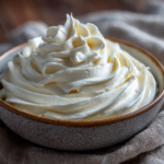 Bowl of fluffy cream cheese frosting with swirls