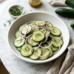 Cucumber salad with vinegar, red onion and fresh dill in a white bowl