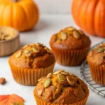 Moist bakery-style pumpkin muffins with crackly sugar tops on a ceramic plate