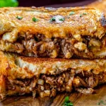 birria grilled cheese sandwich with melted cheese and shredded beef on toasted bread