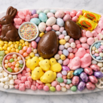 step by step Easter candy charcuterie board preparation on marble board with chocolate eggs and pastel candies