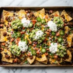 Loaded nachos recipe on a sheet pan with melted cheese and toppings