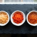 Masago, tobiko and ikura fish roe in three small dishes side by side